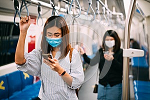 Young asian woman wearing protective face mask using smartphone in underground train due to the polluted air or pm 2.5 and