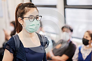 Young Asian woman wearing Surgical face mask against Novel coronavirus or Corona Virus Disease Covid-19 at public subway train.