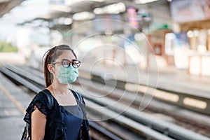 Young Asian woman wearing Surgical face mask against Novel coronavirus or Corona Virus Disease Covid-19 at public train station