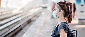 Young Asian woman wearing Surgical face mask against Novel coronavirus or Corona Virus Disease Covid-19 at public train station photo