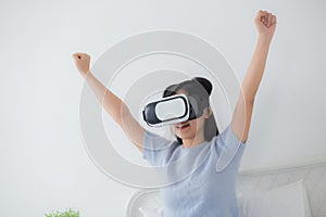 Young asian woman wearing vr headset playing game with excited in the bedroom at home.