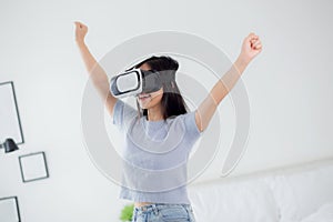 Young asian woman wearing vr headset playing game with excited in the bedroom at home.