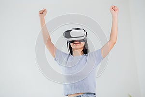 Young asian woman wearing vr headset playing game with excited in the bedroom at home.