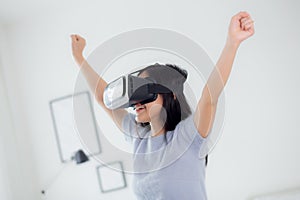 Young asian woman wearing vr headset playing game with excited in the bedroom at home.