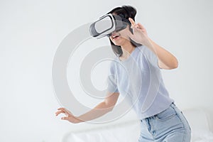 Young asian woman wearing vr headset playing game with excited in the bedroom at home.
