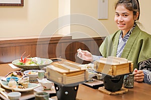 Young Asian woman wearing Yukata with Japanese Dinner set and appetizer on wooden table in Traditional ryokan resort at
