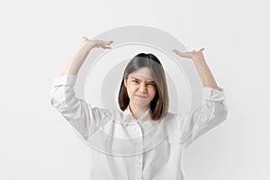 Young Asian woman in white casual clothes attempt to hold something heavy from above.