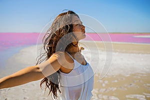 Young asian woman in white meditating near pink lake, practicing Yoga standing on the beach.