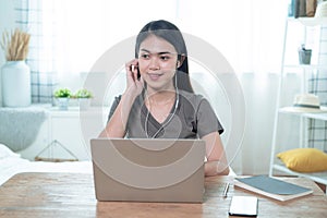 Young Asian woman who loves music, sits at work and listens to music on a casual day in her home