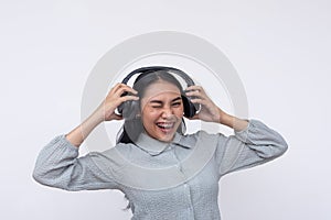 A young asian woman winks while listening to great music on her wireless headphones.  on a white background
