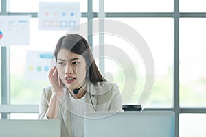 Young asian woman working at a call center Consulting about stock investment information with customers calling for advice with