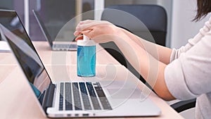 Young asian woman working with computer laptop and using hand sanitizer gel for prevent the pandemic of Covid-19 and Coronavirus,