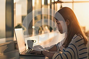 Young asian woman working on a laptop and sit at home office in morning time