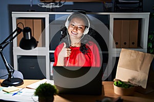 Young asian woman working at the office with laptop at night doing happy thumbs up gesture with hand