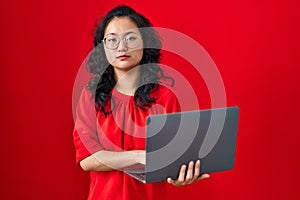 Young asian woman working using computer laptop thinking attitude and sober expression looking self confident