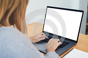 Young Asian woman working using and typing on laptop with mock up blank white screen while at home in office work space.