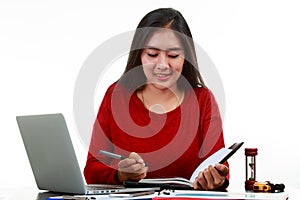 Young Asian woman writing the memo while checking sale volume graph with smiling