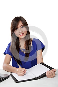 Young Asian woman writing on notebook on a table, isolated on white