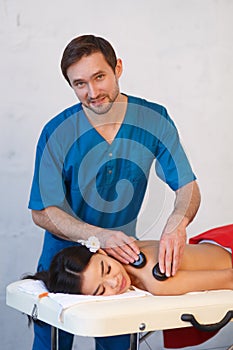 Young Asian woman enjoying the therapeutic effects of a traditional hot stone massage at luxury spa and wellness center