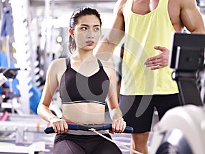 Young asian adult woman exercising using rowing machine