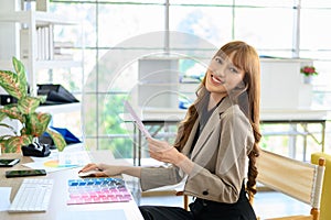 Young Asian Women graphic designer working with diagrams color and computer graphic at office. Look at camera