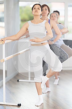 Woman learning passe retire in ballet class for beginners photo