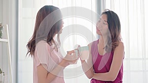 Young Asian women lesbian happy couple talking and drinking coffee in bedroom at home..