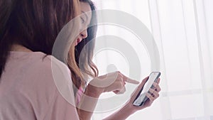 Young Asian women lesbian happy couple using smartphone checking social media in bedroom at home.