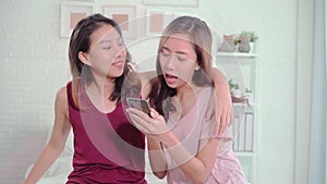 Young Asian women lesbian happy couple using smartphone checking social media in bedroom at home.