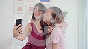 Young Asian women lesbian happy couple using smartphone checking social media in bedroom at home.