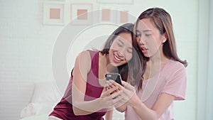 Young Asian women lesbian happy couple using smartphone checking social media in bedroom at home.