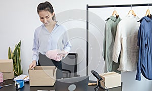 Young Asian women pack their clothes into boxes and prepare them to be delivered by post, Online clothing sales business, Business