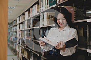 Young Asian women are searching for books and reading books on the tables and aisles of the college libraries to research and