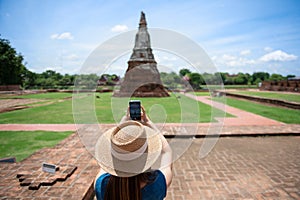 Young Asian women tourist taking photo picture with camera and traveling at Wat Chaiwatthanaram, ancient buddhist temple, famous