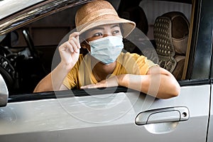 Young Asian women wear a mask due to air pollution or a viral epidemic before traveling in their car. Virus protection concept