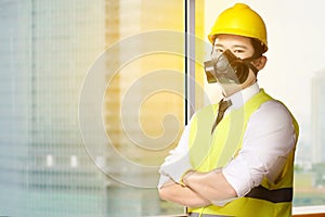 Young asian worker man in safety vest, gloves, yellow helmet and protective mask standing