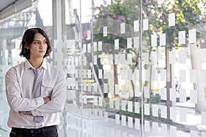 Young Asian worker stands using a laptop in an office building