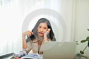Young Asian worker woman working with laptop computer. A woman thinking of some idea and feeling stress while working from home