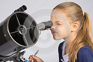 The young astronomer looks through the eyepiece of the telescope and record results