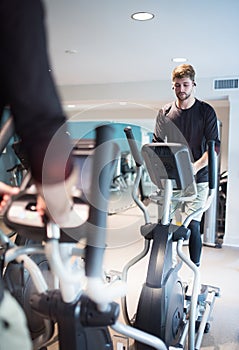 young athlete doing elyptical bike in fitness gym attractive young man working out leg muscles in gym