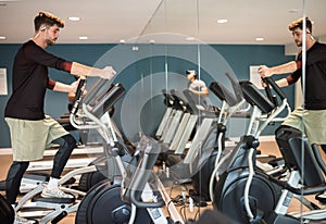 young athlete doing elyptical bike in fitness gym attractive young man working out leg muscles in gym