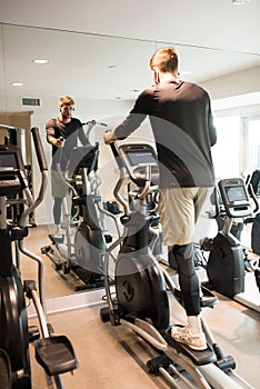 young athlete doing elyptical bike in fitness gym attractive young man working out leg muscles in gym