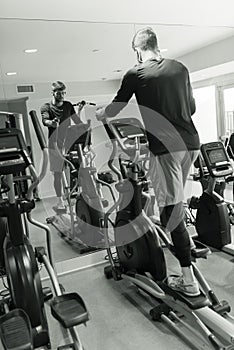 young athlete doing elyptical bike in fitness gym attractive young man working out leg muscles in gym