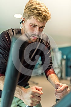 young athlete doing elyptical bike in fitness gym attractive young man working out leg muscles in gym