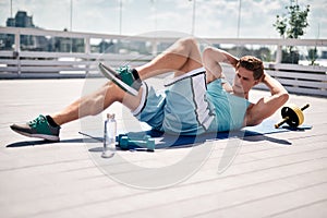 Young athlete is doing side crunches on roof