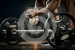 Young athlete getting ready for weight lifting training. Powerlifter hand in talc preparing to bench press