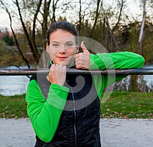 Young athlete giving thumbs up while doing pullups.