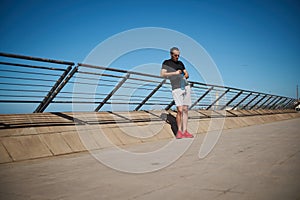 Young athlete holding bottle of water on the beach after morning jog or bodyweight training on the outdoor sportsground