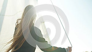 A young athlete learns to set sail on a yacht during a training race on sailing vessels. Bright glare of the sun in the