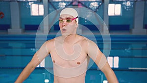 A young athlete male swimmer man puts on swimming goggles and does a warm-up before the swim. Portrait of a professional